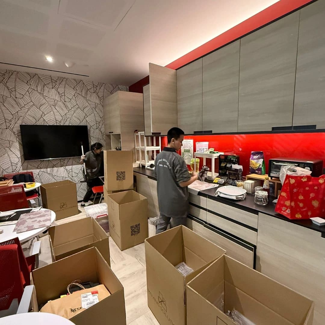 Moving crew packing kitchen belongings into cartons